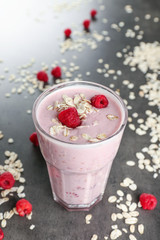Fresh milkshake with raspberry and oatmeal on grey textured background
