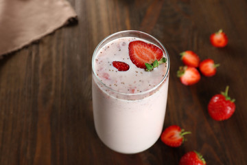 Fresh milkshake with strawberry on wooden background