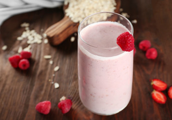 Fresh milkshake with berries and oatmeal on wooden background
