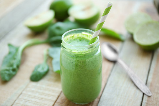 Fresh milkshake with spinach on wooden table closeup