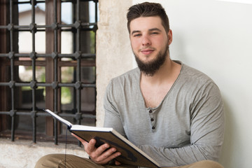 Young Muslim Guy Reading The Koran