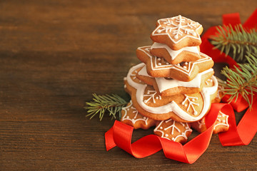 Stack of tasty gingerbread cookies, ribbon and Christmas tree branch on wooden background, close up view