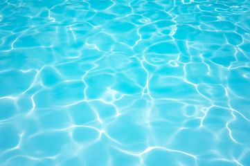Fototapeta na wymiar Ripple blue water surface in swimming pool with sun reflection