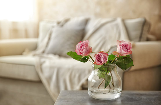 Fresh roses in glass vase on table in the room