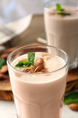 Glass with delicious nut milk shake on table, closeup