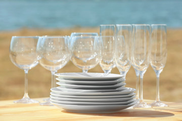 Wooden table with plates and glasses outdoors, close up view
