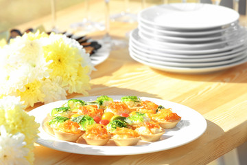 Plate with tasty tartlets on wooden table, close up view
