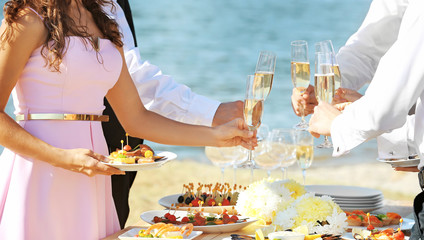 People clinking glasses at buffet catering party outdoors near river