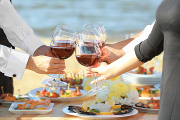 People clinking glasses at buffet catering party outdoors, close up