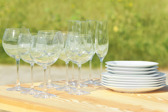 Wooden table with plates and glasses outdoors, close up view