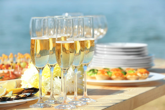 Glasses of champagne on table served for buffet catering party outdoors, close up