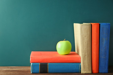 Books and apple on blackboard background