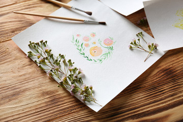 Watercolor painting with flowers on wooden table