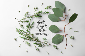 Quote "Dont forget to be awesome" written on paper with leaves and flowers on white background. Top view