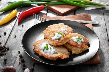 Plate with tasty potato pancakes for Hanukkah and some ingredients on wooden table