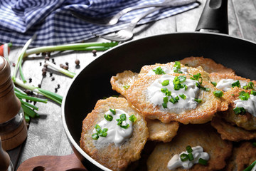Frying pan with tasty potato pancakes for Hanukkah on wooden table, closeup