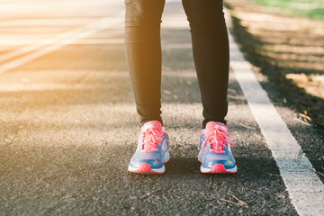 Young lady running on road closeup on shoe., at time sunset