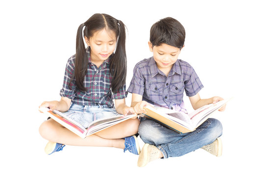 10 and 7 years Asian school girl and boy happily sitting and reading book together isolated over white