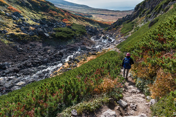 Obraz premium Woman hiking down into a ravine toward a hot spring, Daisetsuzan, Hokkaido, Japan