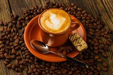 cup of cappuccino, milk-chocolate wafer and coffee beans