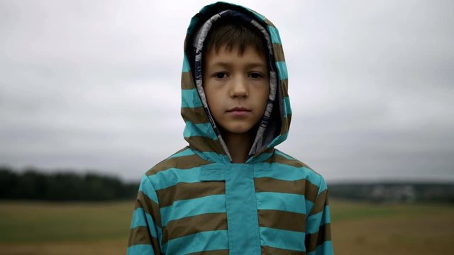 Portrait of a boy in the hood standing and looking at the camera in the evening