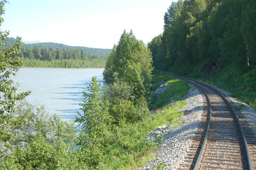 Train rolling past lake and mountain