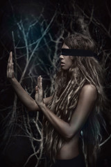 Young beautiful blindfolded woman in forest