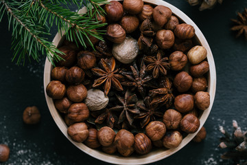 Hazelnuts, star anise, nutmeg in wooden plate, top view