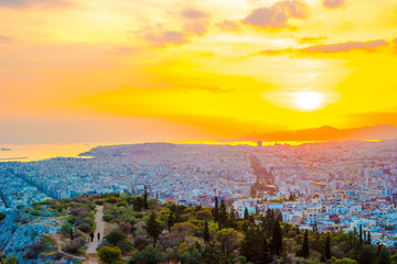Panorama of Athens at sunset. Beautiful cityscape with seashore and distant islands visible under the red sunset sky. Travel photography.