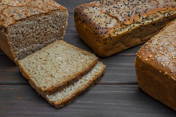 Homemade bread with seeds on dark brown wooden background.
