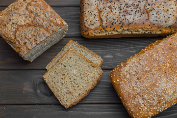 Homemade bread with seeds on dark brown wooden background.