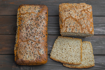 Homemade bread with seeds on dark brown wooden background.