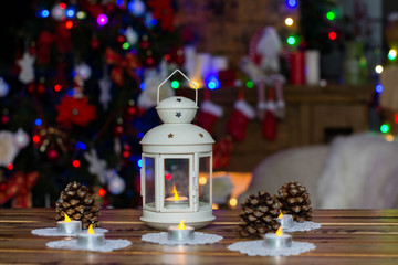 Christmas Decorations with candle, cone on wooden table against lights background