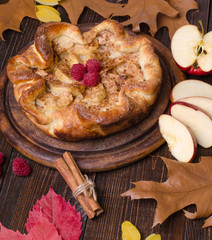Apple pie with cinnamon and raspberry on a wooden table. Vertical.