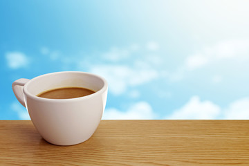 A cup of coffee on table over sky background