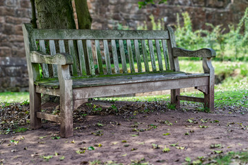 hölzerne, alte Bank allein im Park vor einer alten Wand