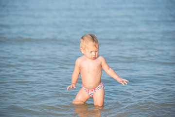 Baby playing on the sandy beach and in sea water. Cute little kid with toys on sand tropical beach. Ocean coast.