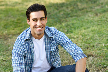 Man sitting on grass of an urban park.