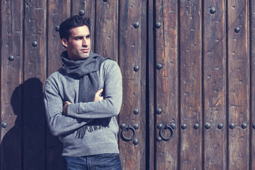 Handsome man wearing winter clothes in wooden background.