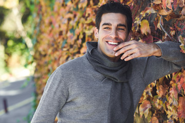 Man wearing winter clothes smiling in autumn leaves background