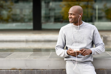 Attractive black man listening to music with headphones in urban