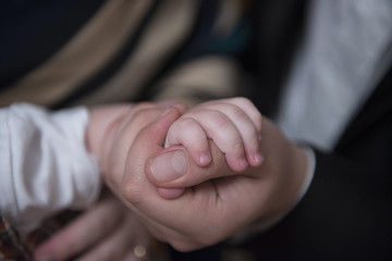 Father holding his little baby's hand in his hand, close-up