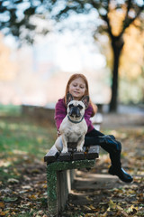 Children and dogs outdoors. Beautiful and happy redhead girl enjoying in autumn park with her adorable French bulldog.