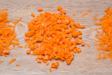 Cut and grated carrot on the wooden table in the kitchen. Healthy eating and lifestyle.
