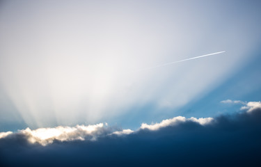 Fototapeta na wymiar Clouds, sun and vapor trails of an airplane