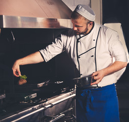 young chef preparing meat in the kitchen interior