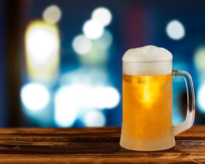 cold glass mug of beer with foam on the background of the street