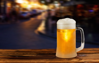 cold glass mug of beer with foam on the background of the street