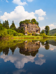 Fototapeta na wymiar Rock castle Sloup v Cechach reflected in the water on sunny day, Northern Bohemia, Czech Republic