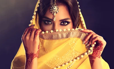 Fotobehang Beautiful indian girl . Young hindu woman model  with tatoo mehndi  and kundan jewelry . Traditional Indian costume yellow saree . Indian or Muslim woman covers her face. © Sofia Zhuravetc